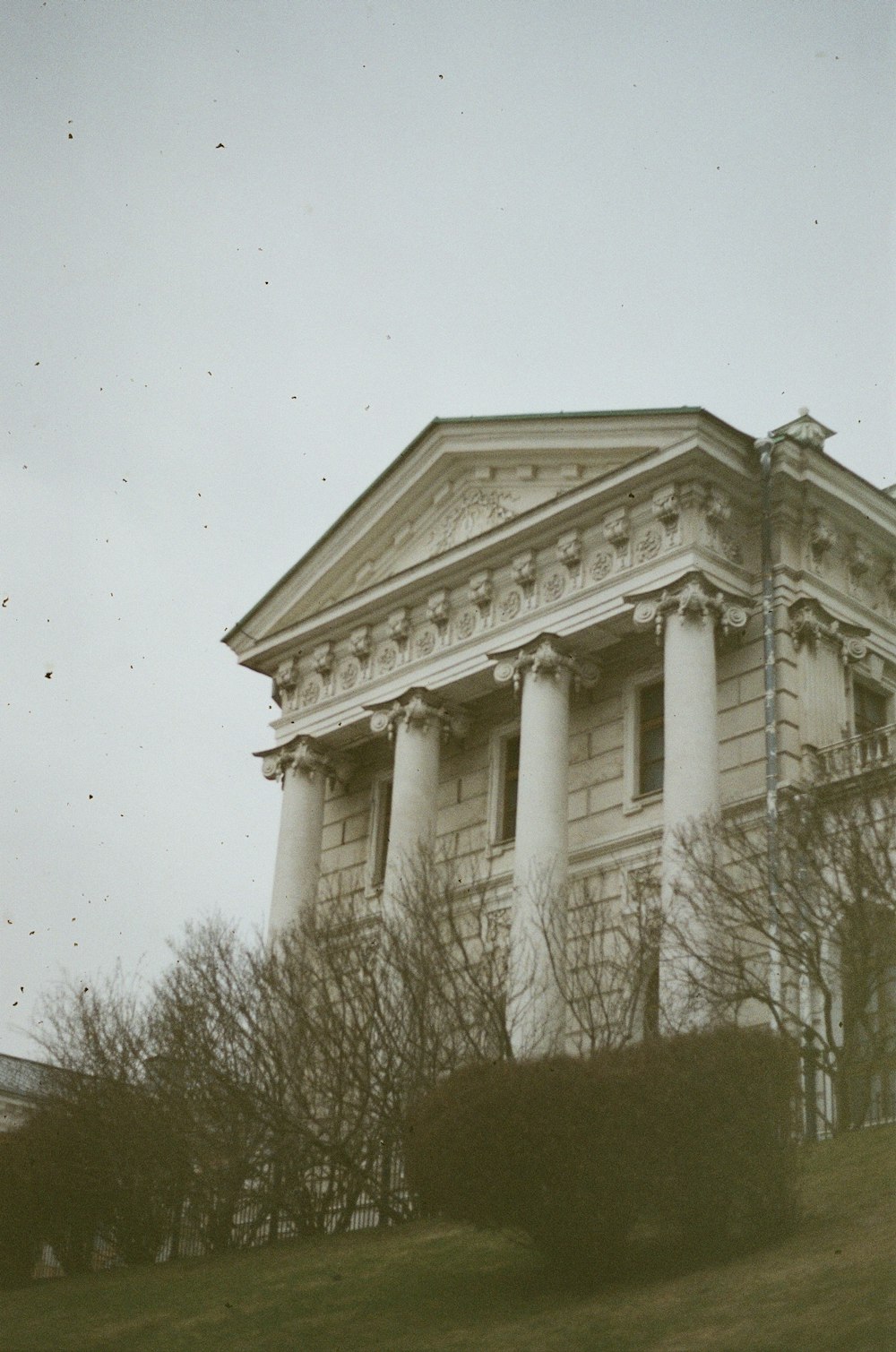 an old building with columns and a clock on the front of it