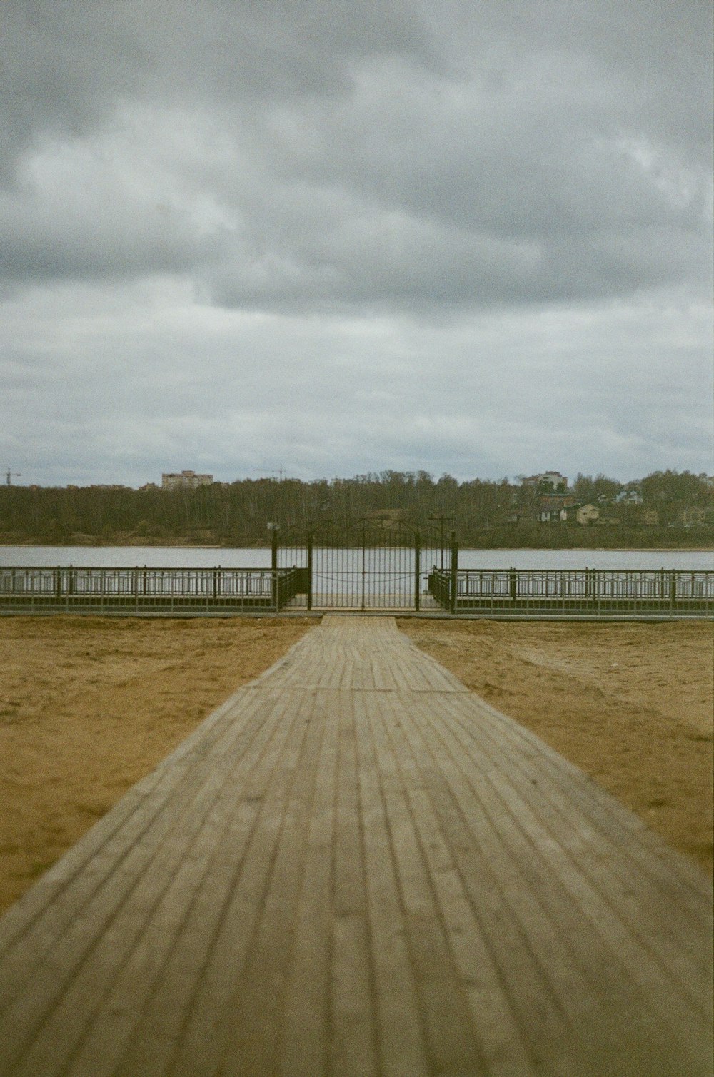 a wooden walkway leading to a beach with a body of water in the background