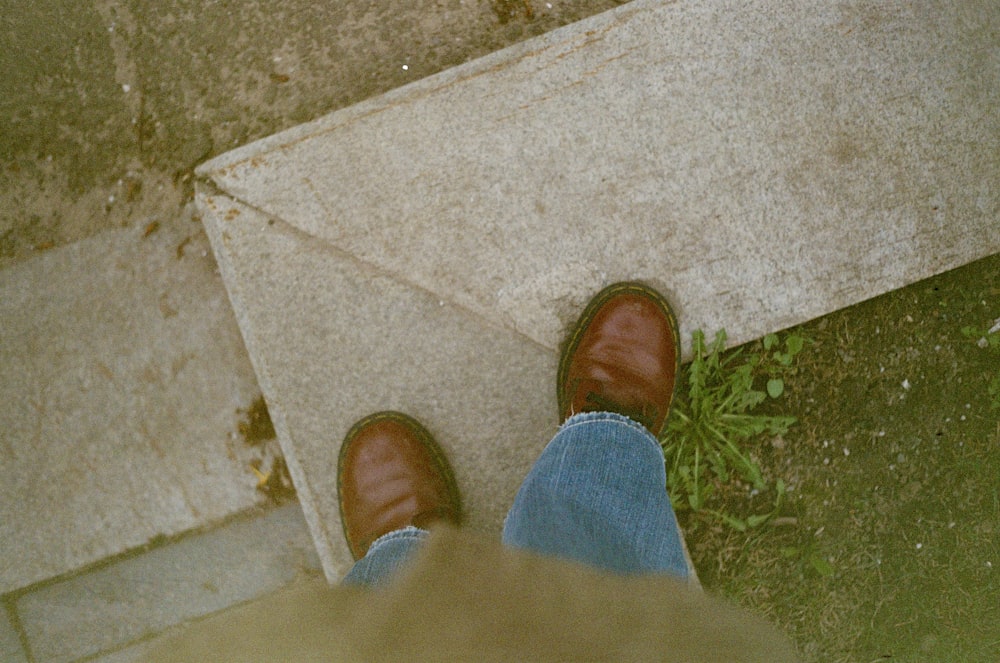 a person wearing brown shoes standing on a sidewalk