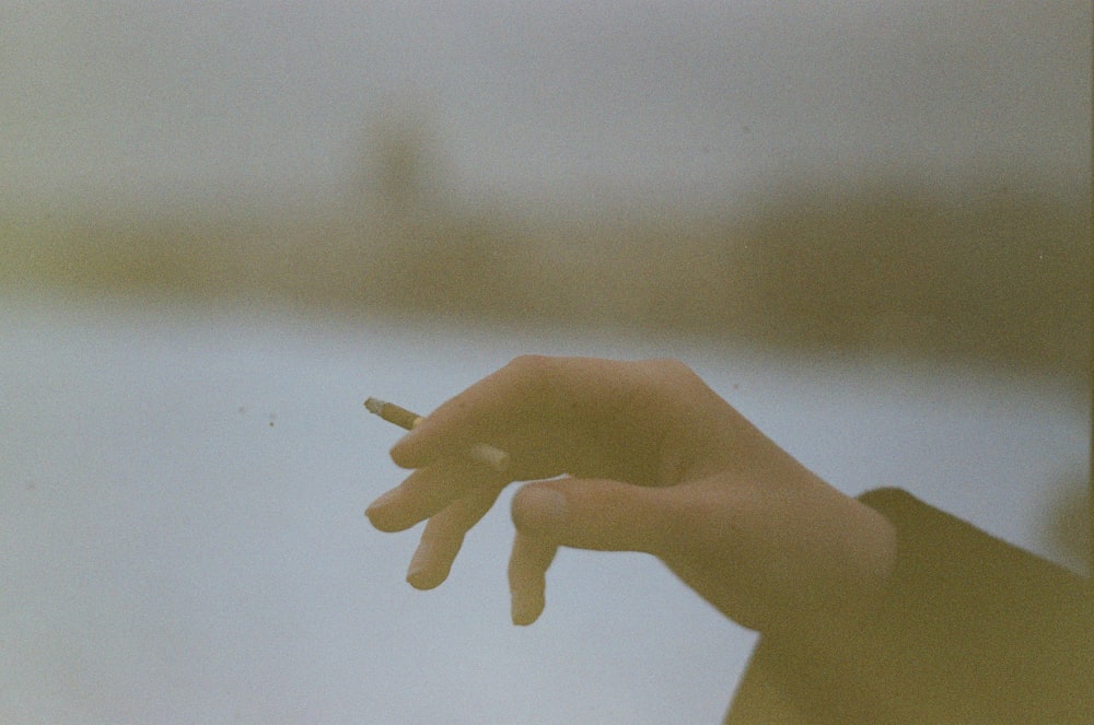 a person holding a cigarette in their hand