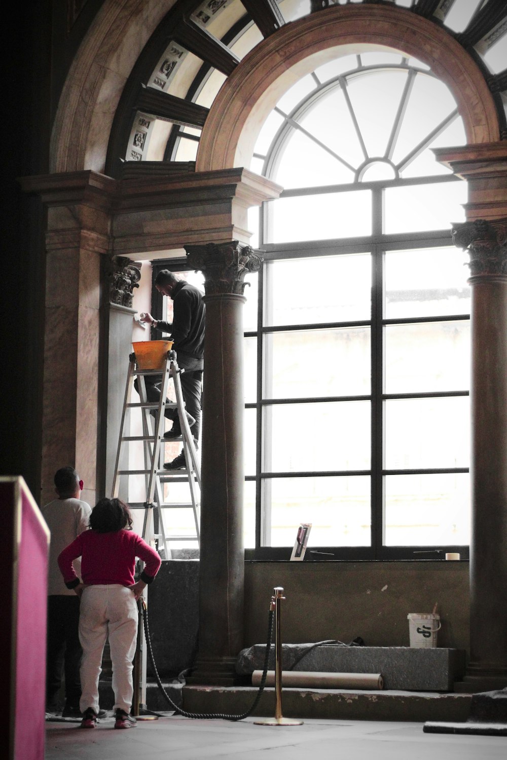 Eine Frau in einem roten Hemd bemalt ein Fenster