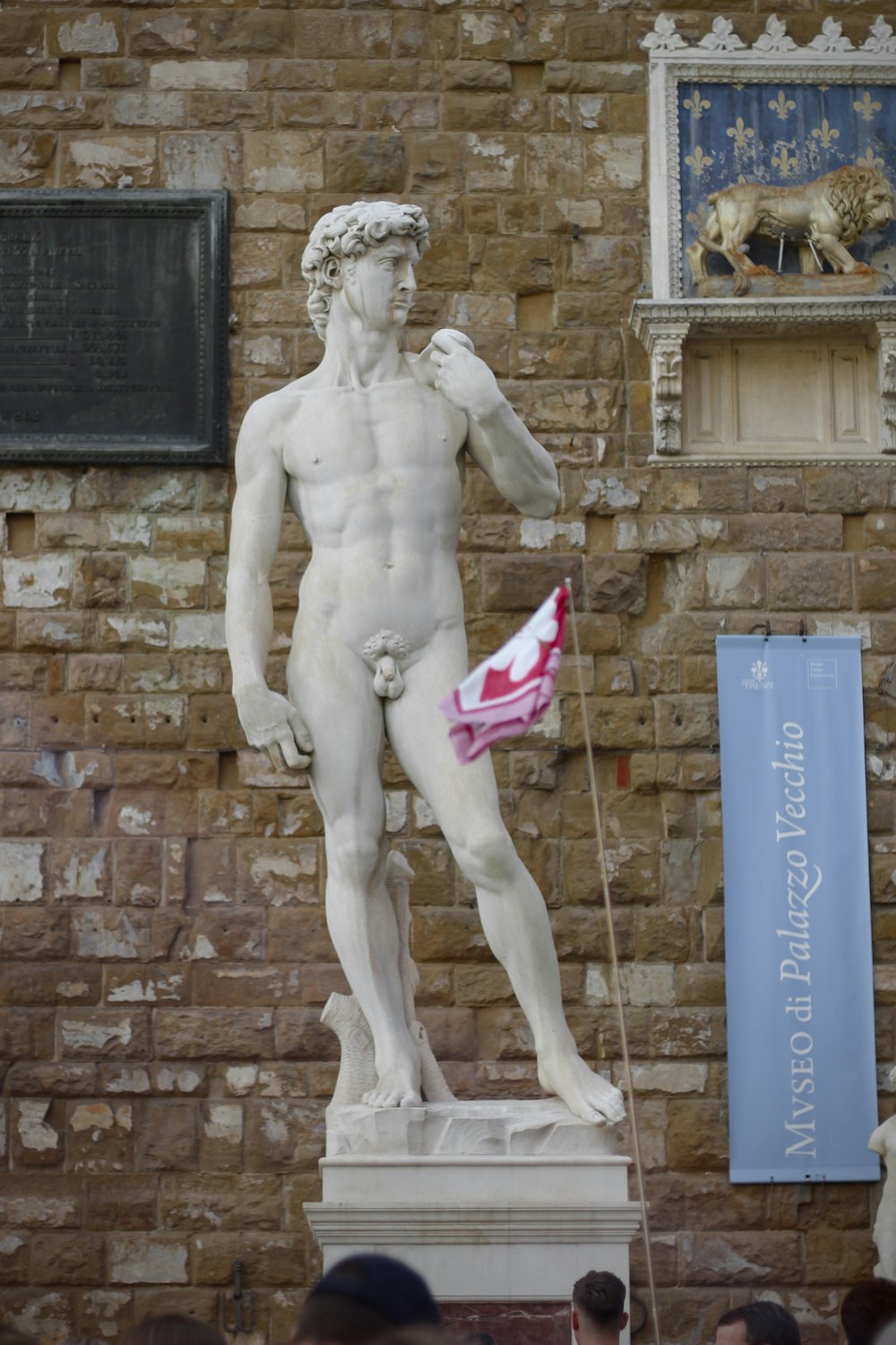 una statua di un uomo che tiene una bandiera davanti a un muro di mattoni