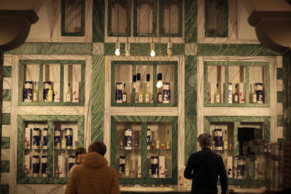 two people standing in front of a display of liquor bottles