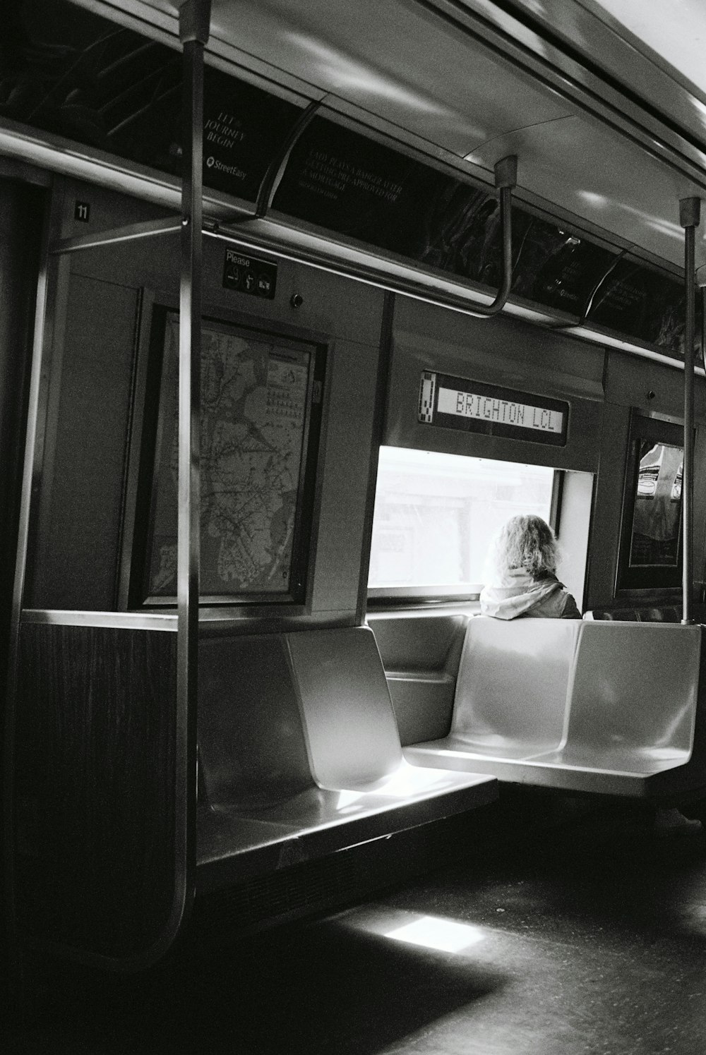 a black and white photo of a woman sitting on a train