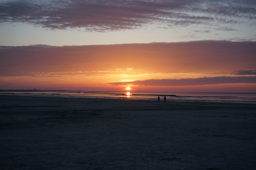 the sun is setting over the ocean on the beach