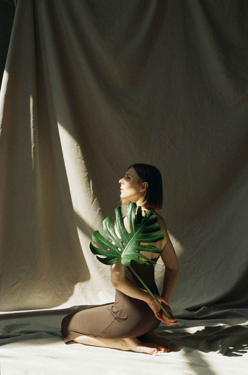 uma mulher sentada no chão segurando uma planta verde