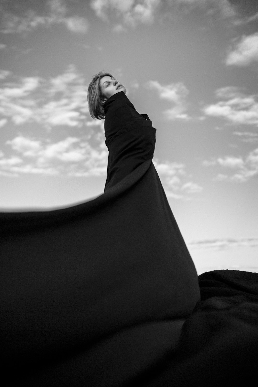 a woman in a long black dress looking up into the sky