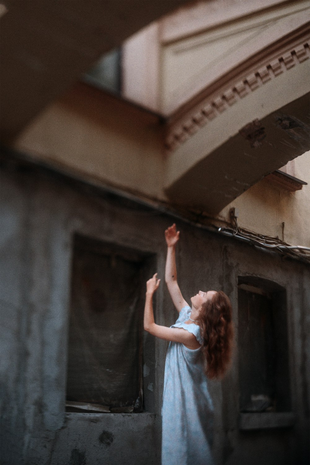 a woman in a blue dress reaching up into the air