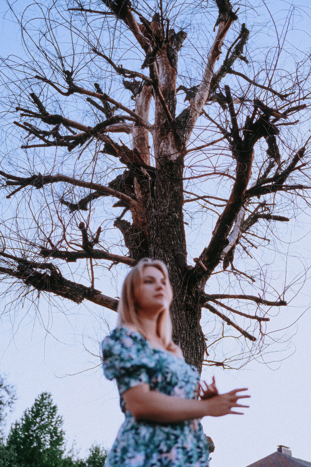 a woman standing in front of a bare tree