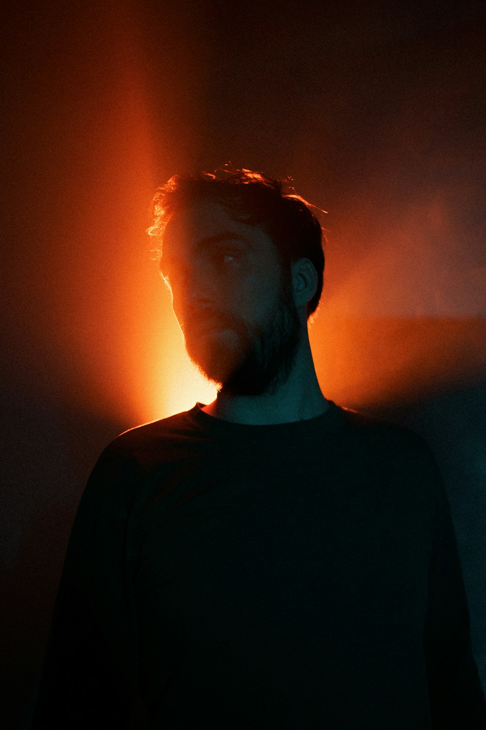 a man with a beard standing in a dark room