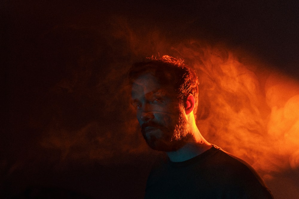 a man with a beard standing in front of a dark background