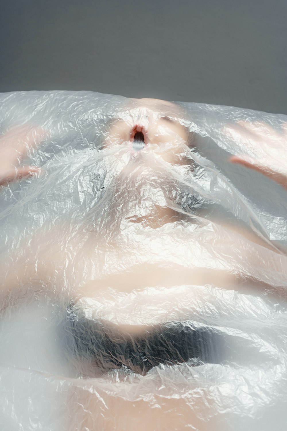 una donna sdraiata in una vasca da bagno ricoperta di plastica