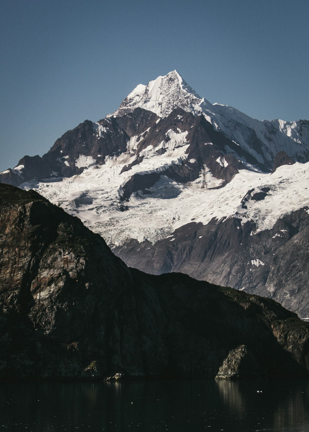 a large mountain covered in snow next to a body of water