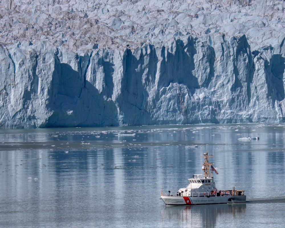 a boat in a body of water near a large iceberg