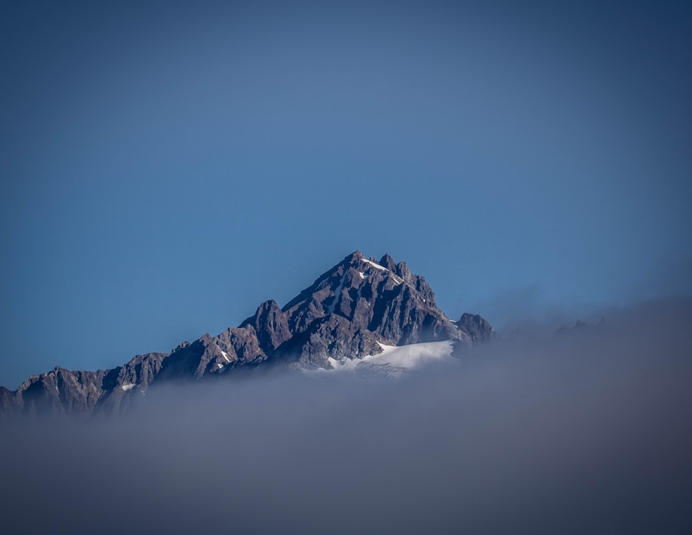 a snow covered mountain in the middle of a cloud filled sky