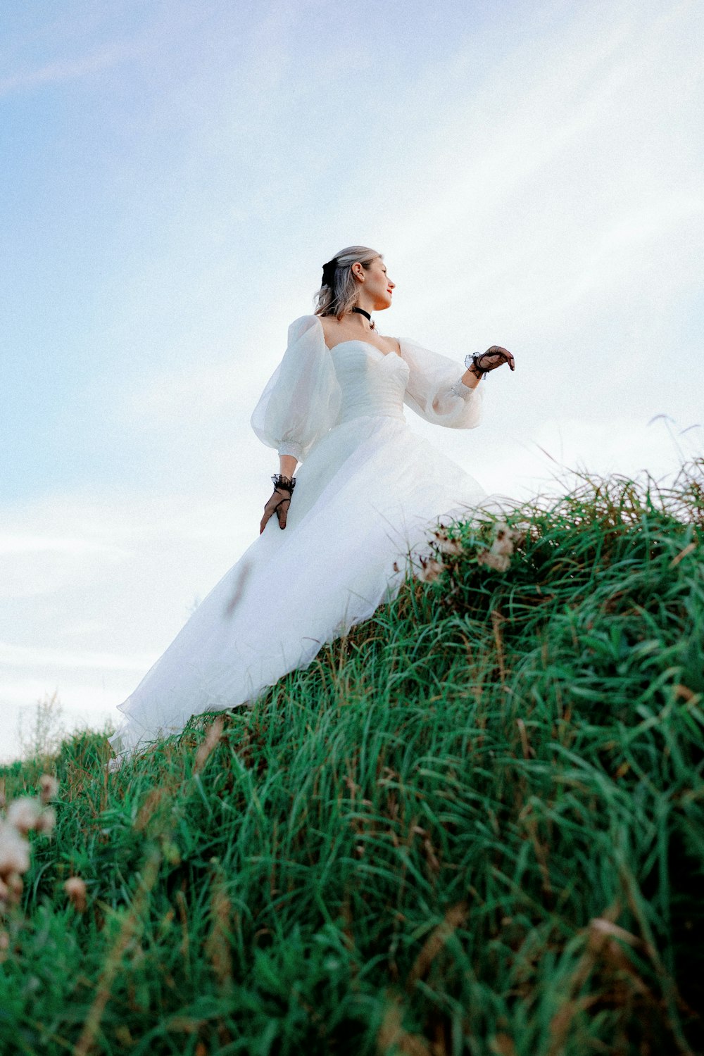 a woman in a wedding dress standing on a hill