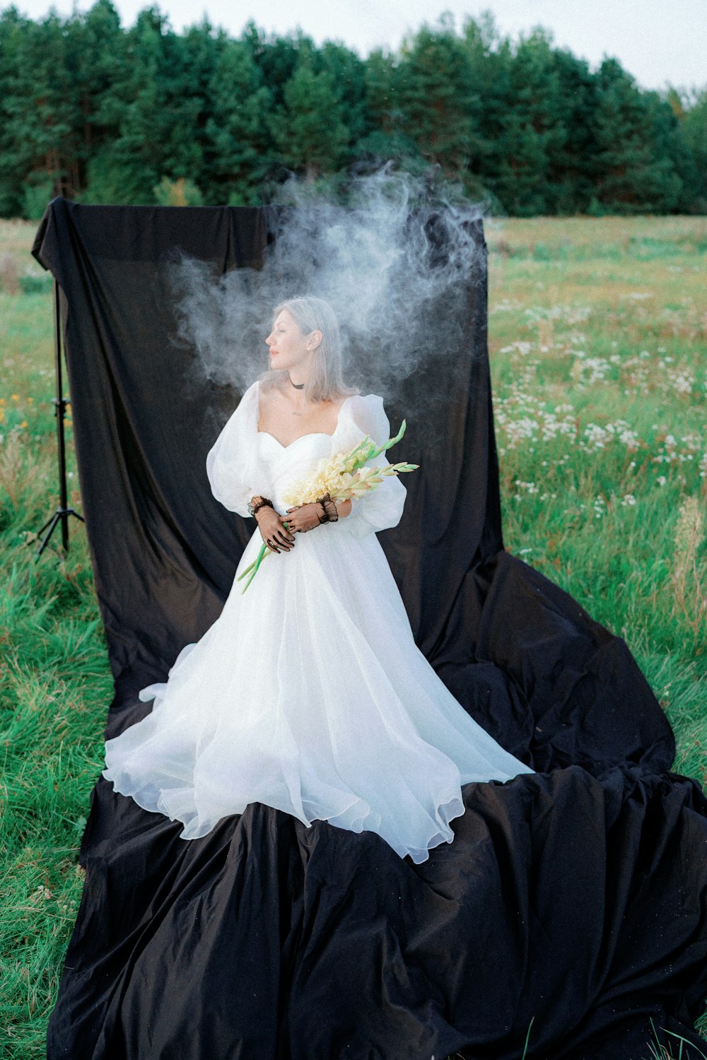 a woman in a white dress sitting in a field