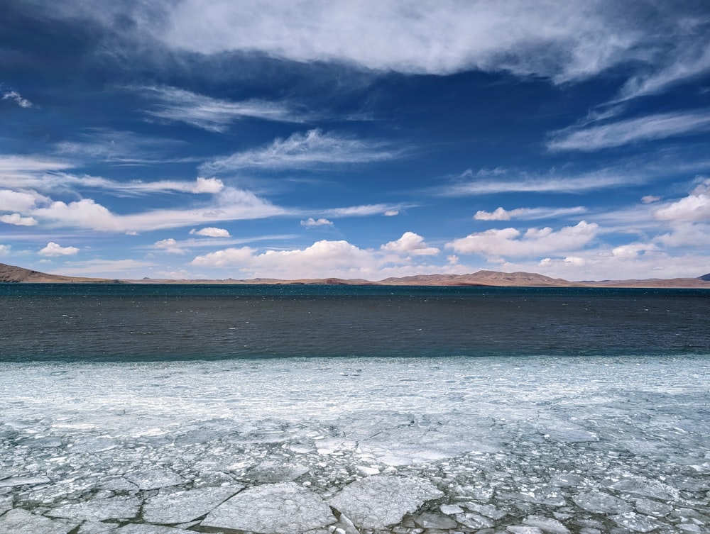 a large body of water sitting under a cloudy blue sky