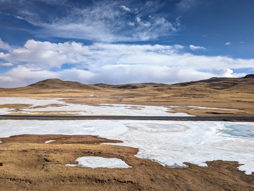 a large open field covered in snow under a blue sky