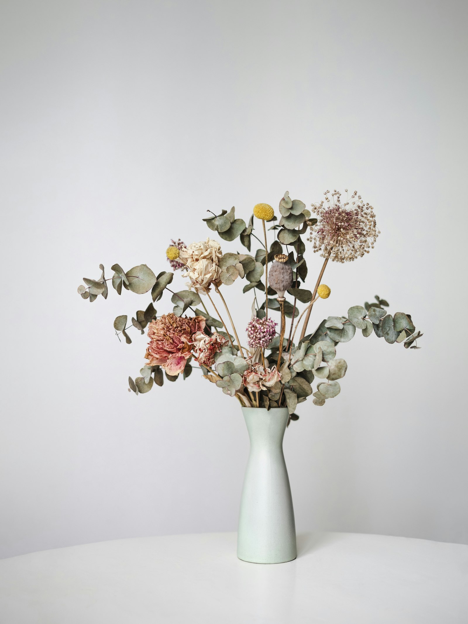 Un vase blanc cassé garni de fleurs séchées