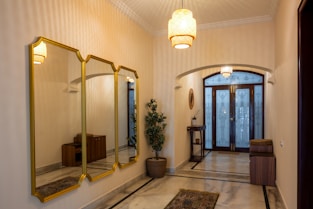 a hallway with three mirrors and a potted plant