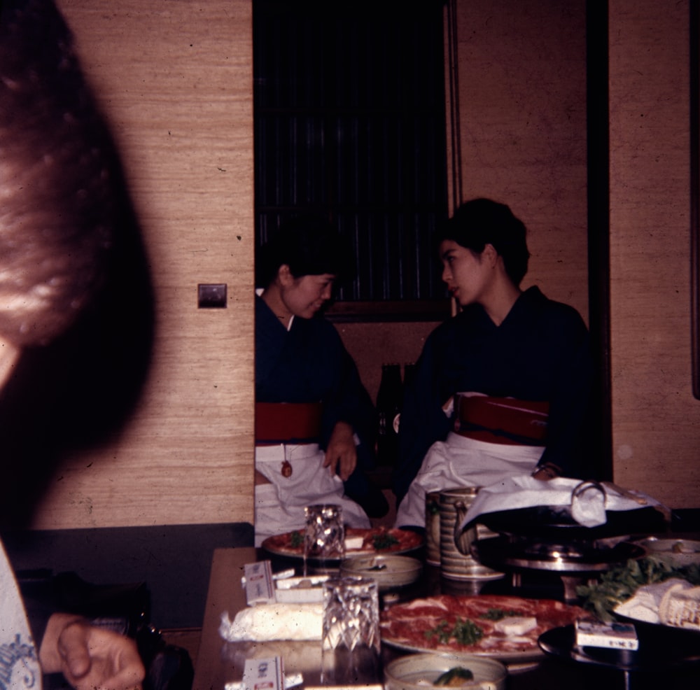 a group of people sitting around a table with food on it