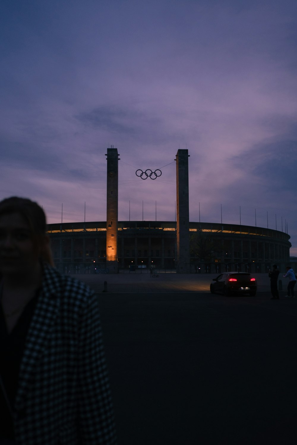 a woman standing in front of a building at dusk