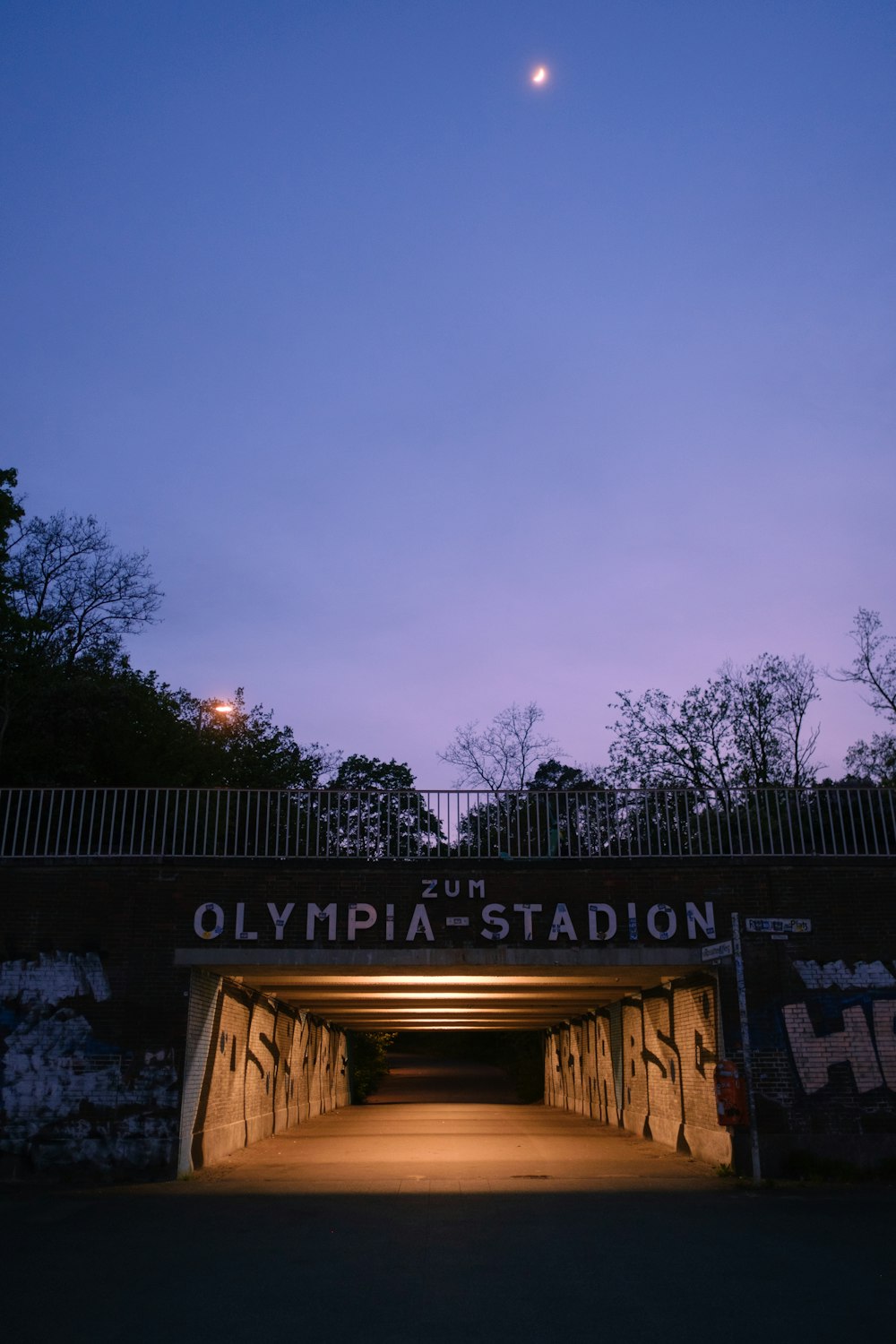 a dark tunnel with graffiti on it and a moon in the sky