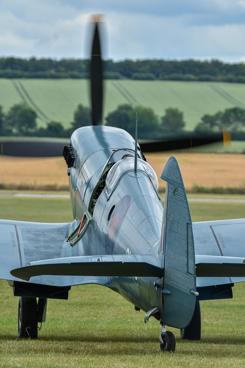 a silver airplane sitting on top of a lush green field