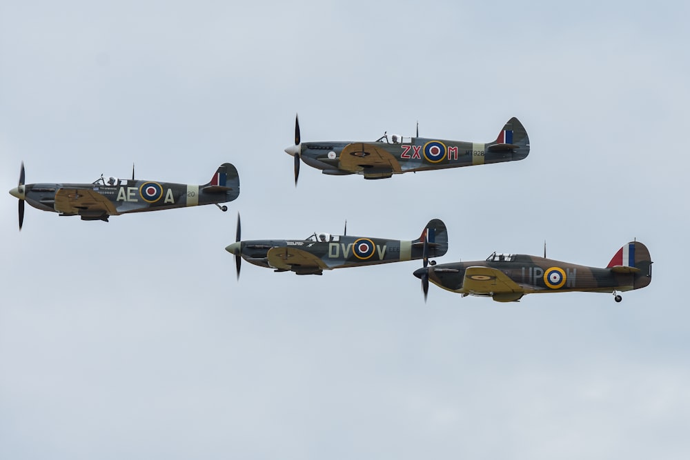 a group of four planes flying through a cloudy sky