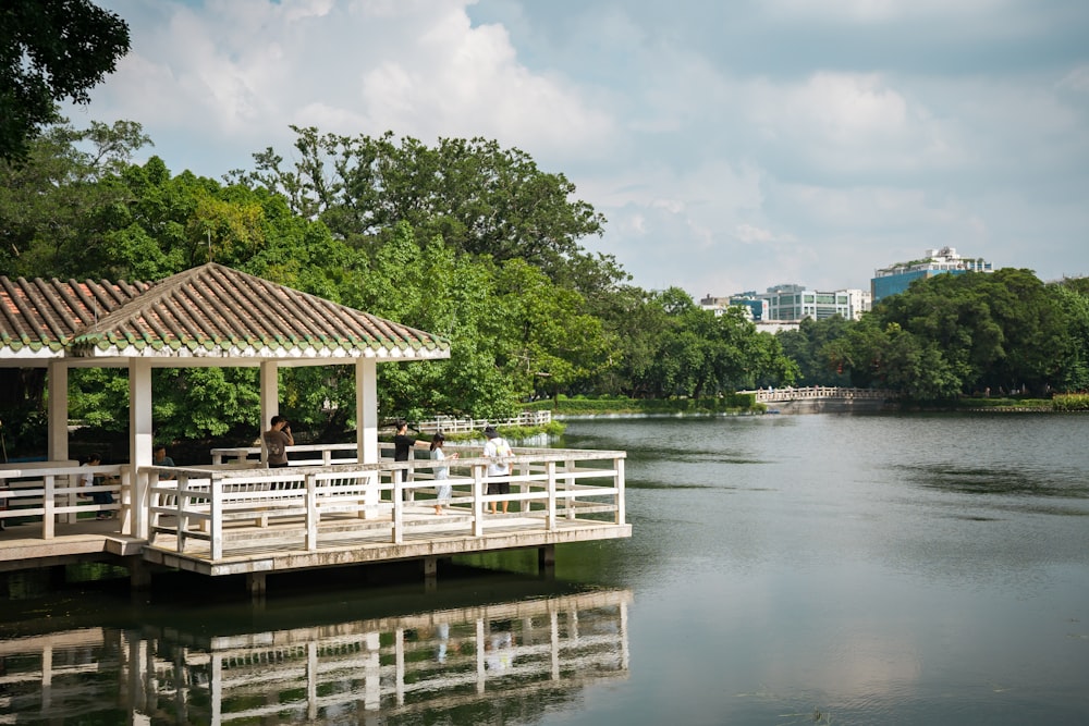 a gazebo sitting on top of a lake next to a forest