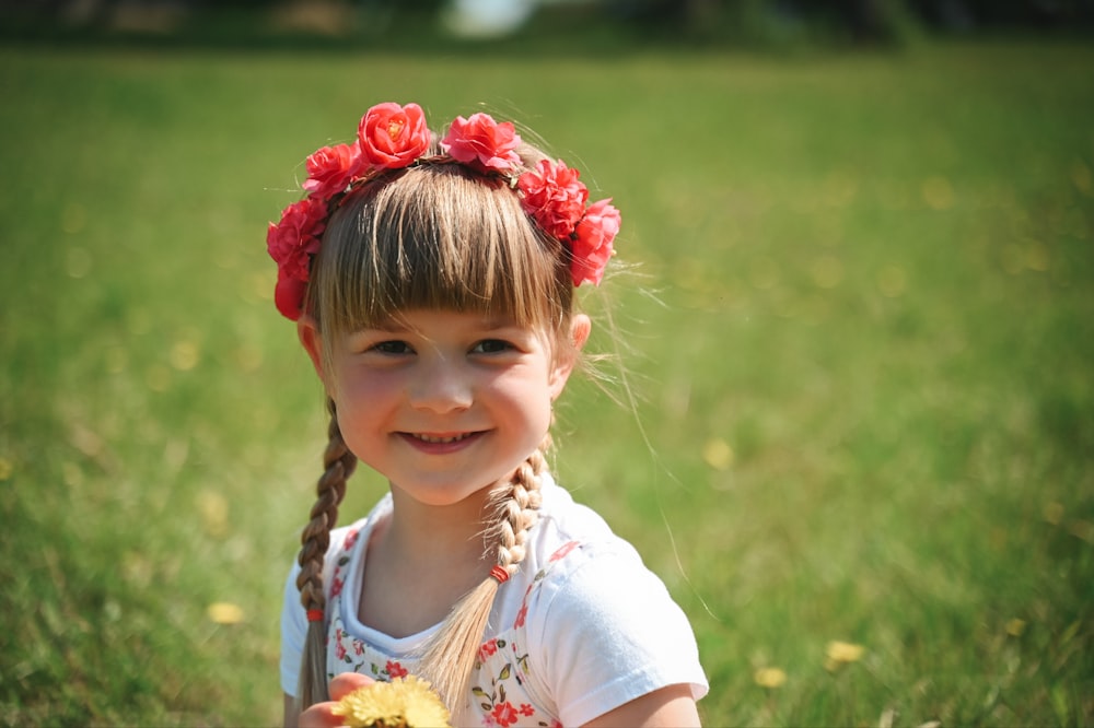 a little girl with a flower in her hair holding an apple