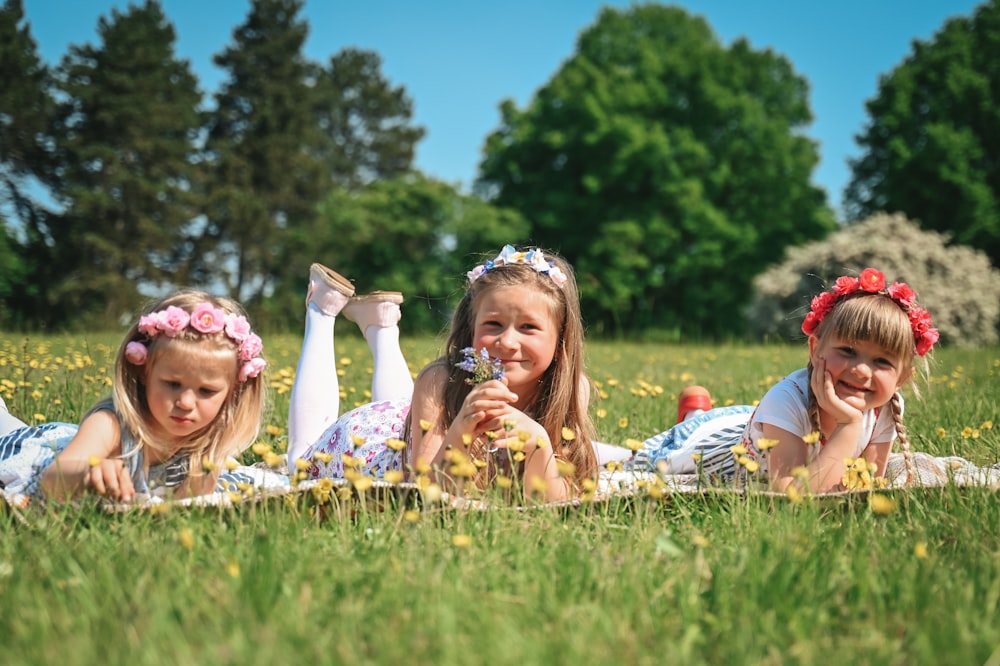 three little girls laying in a field of grass