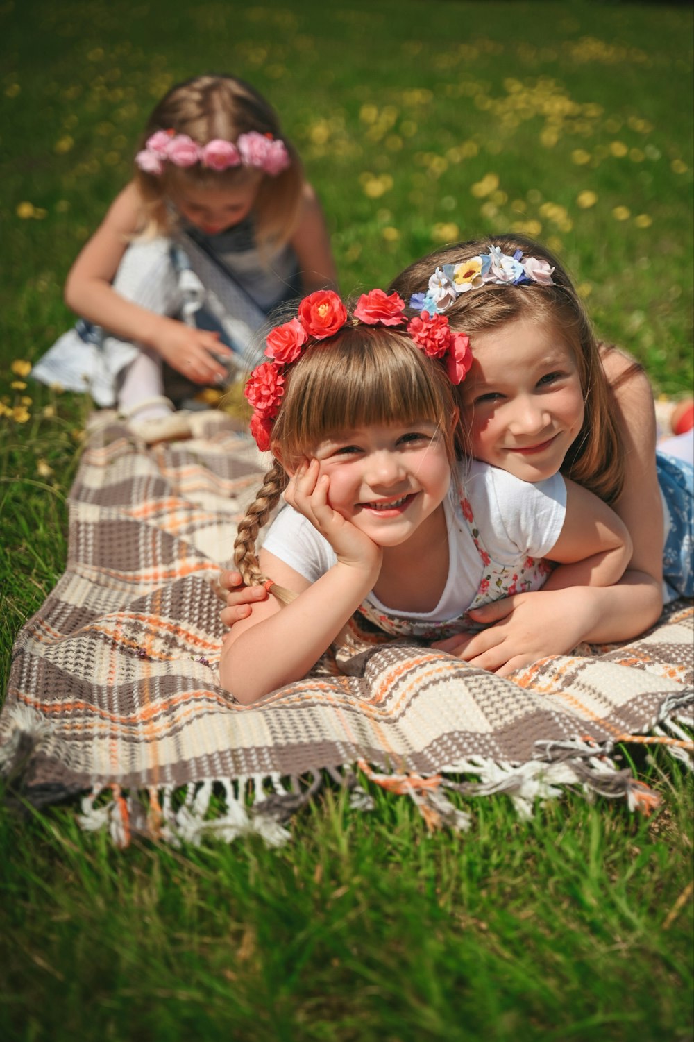 two little girls laying on a blanket in the grass