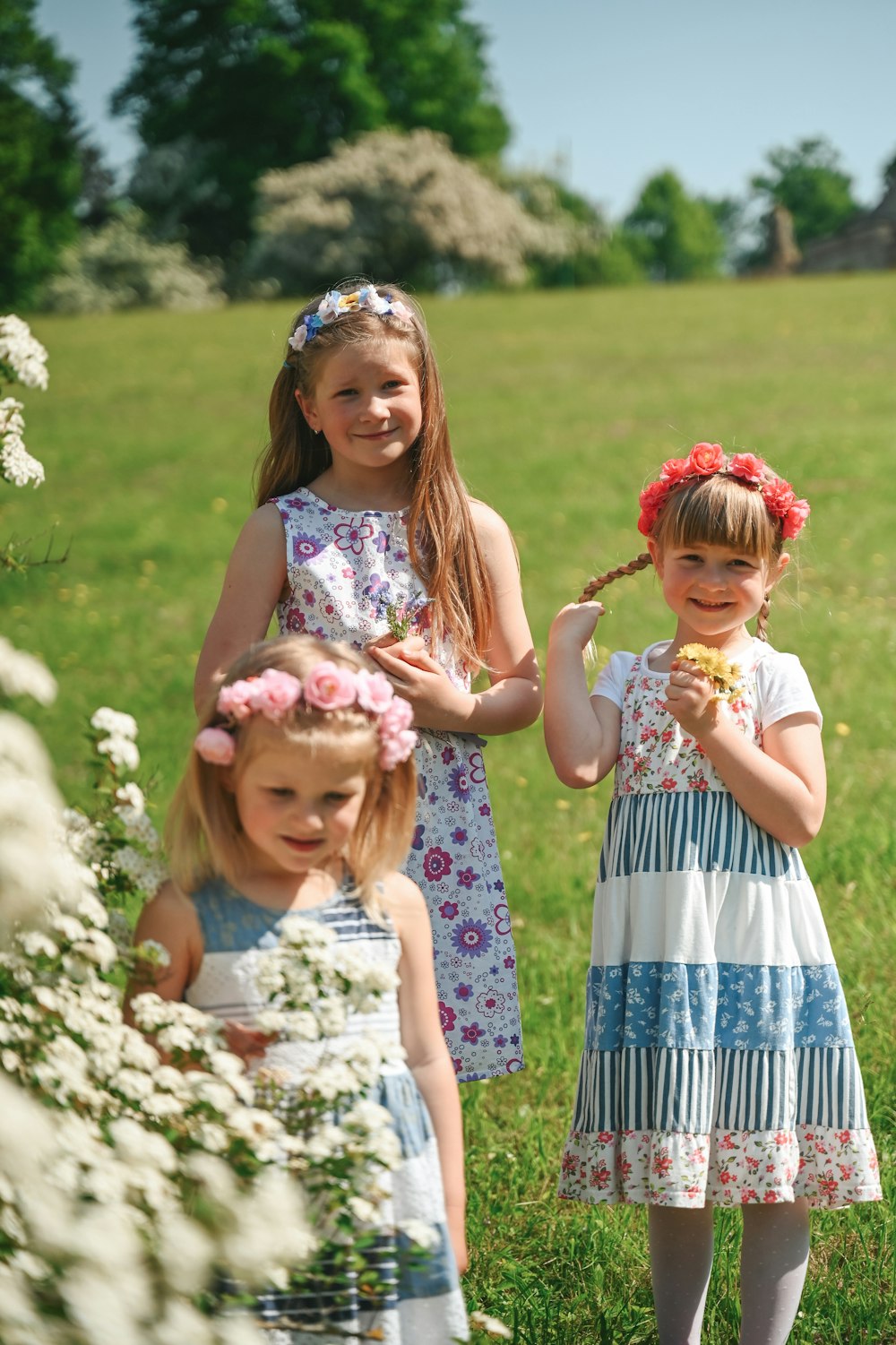 three little girls are standing in a field