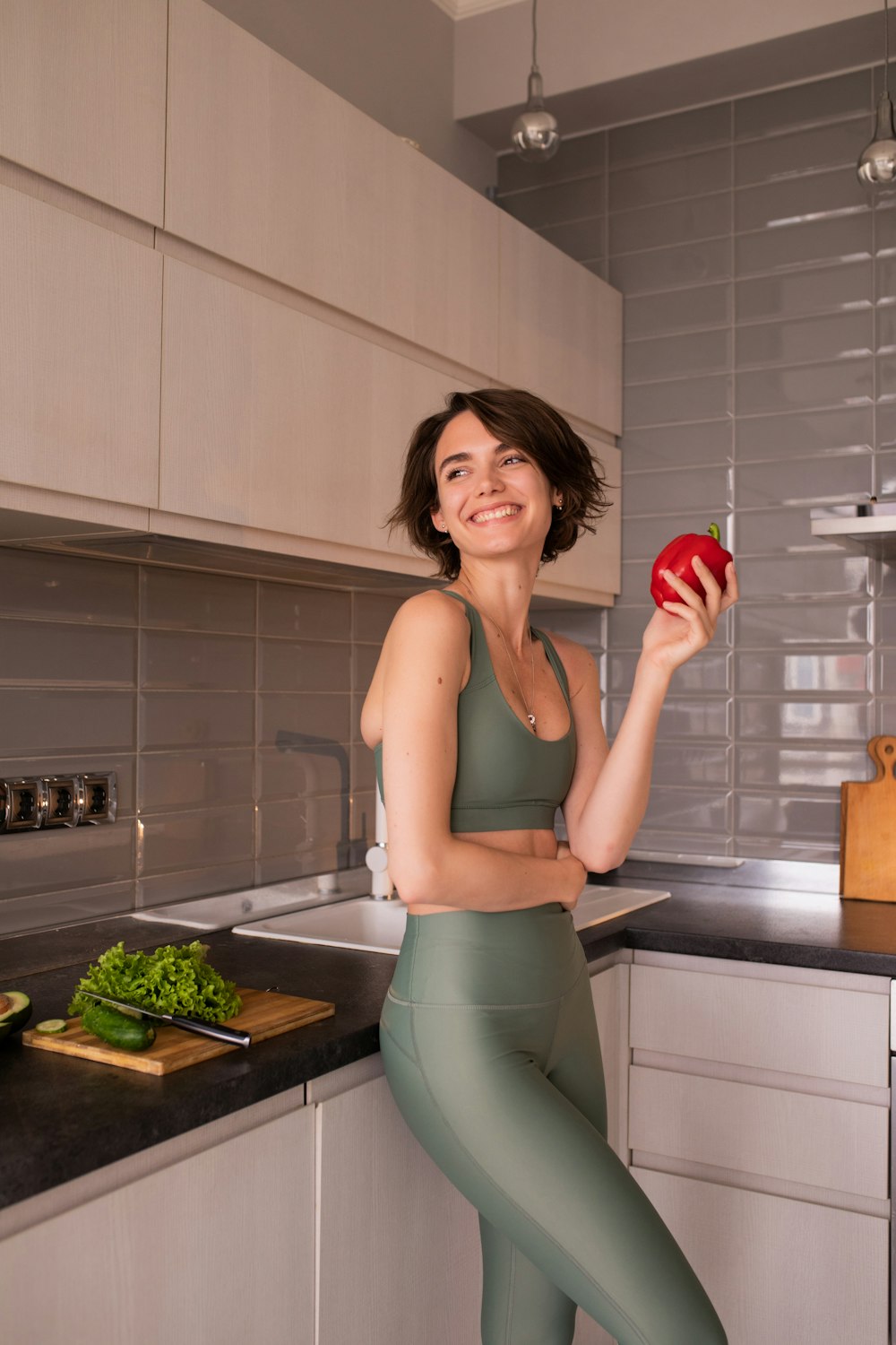 a woman standing in a kitchen holding an apple