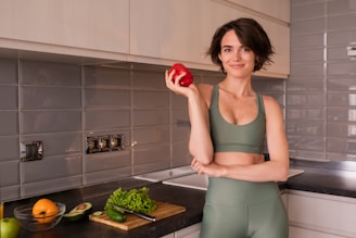 a woman standing in a kitchen holding an apple
