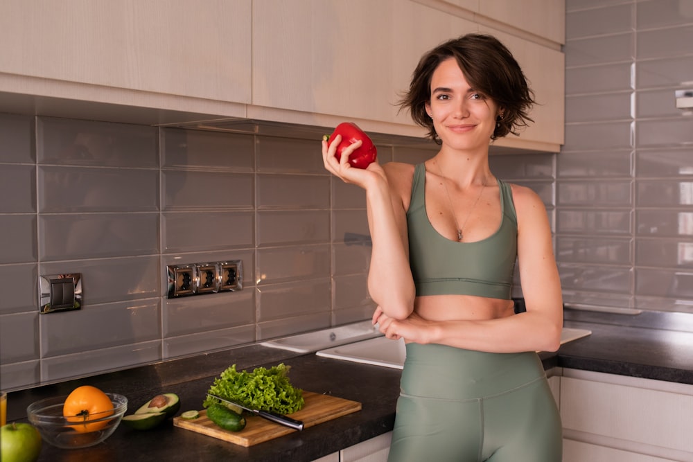 a woman standing in a kitchen holding an apple