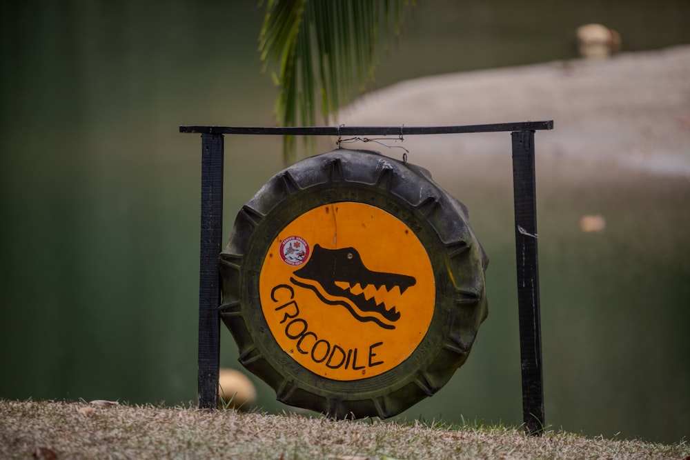 a sign with a crocodile on it in front of a body of water
