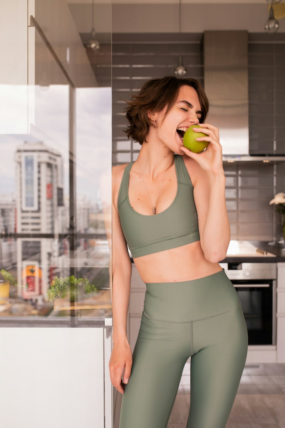 uma mulher em pé em uma cozinha segurando uma maçã verde