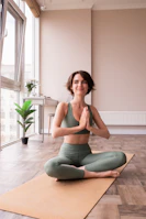 a woman sitting on a yoga mat in a room