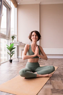a woman sitting on a yoga mat in a room