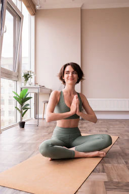 a woman sitting on a yoga mat in a room