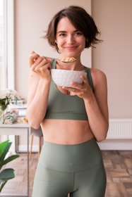 a woman in a sports bra top holding a bowl of food