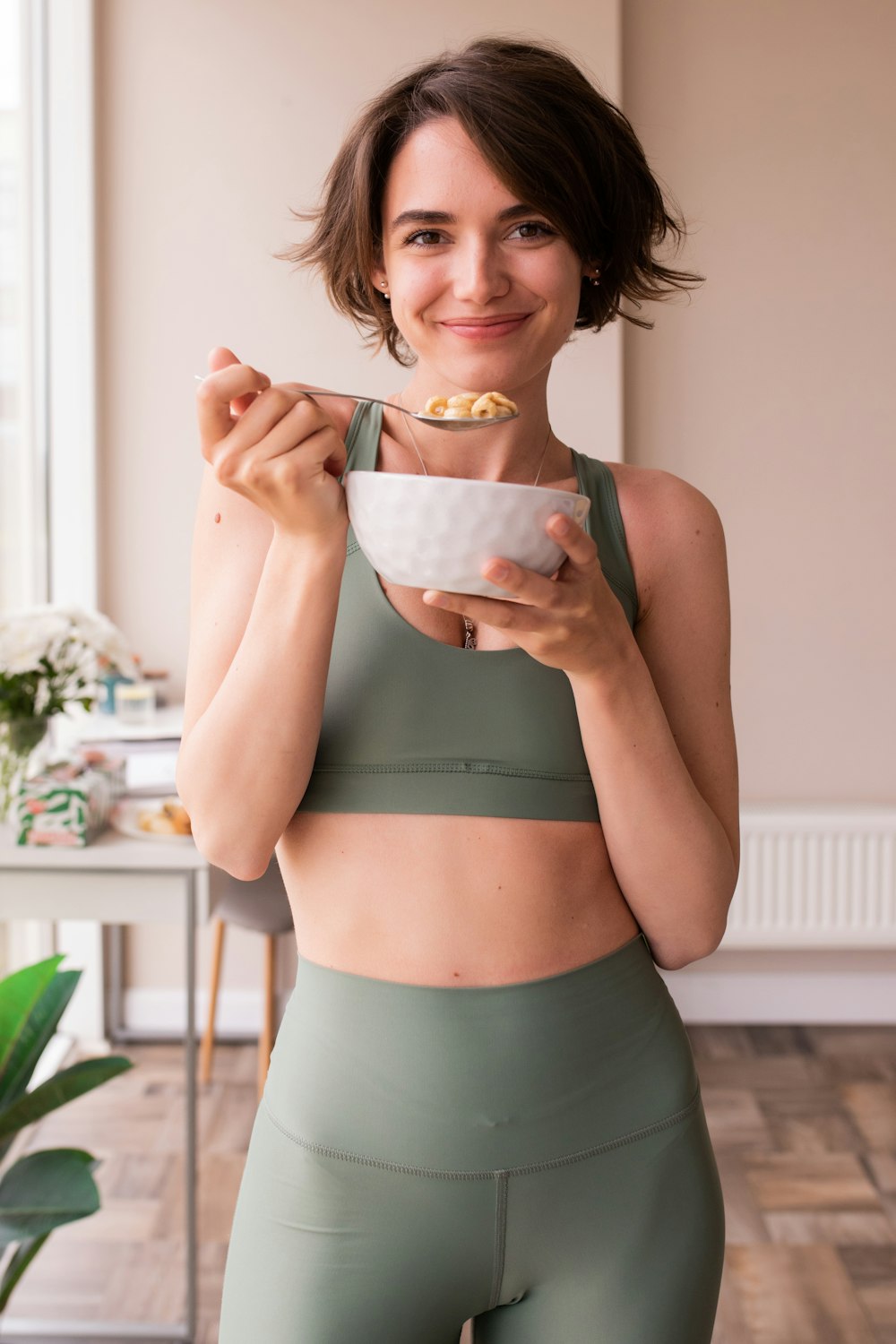 a woman in a sports bra top holding a bowl of food