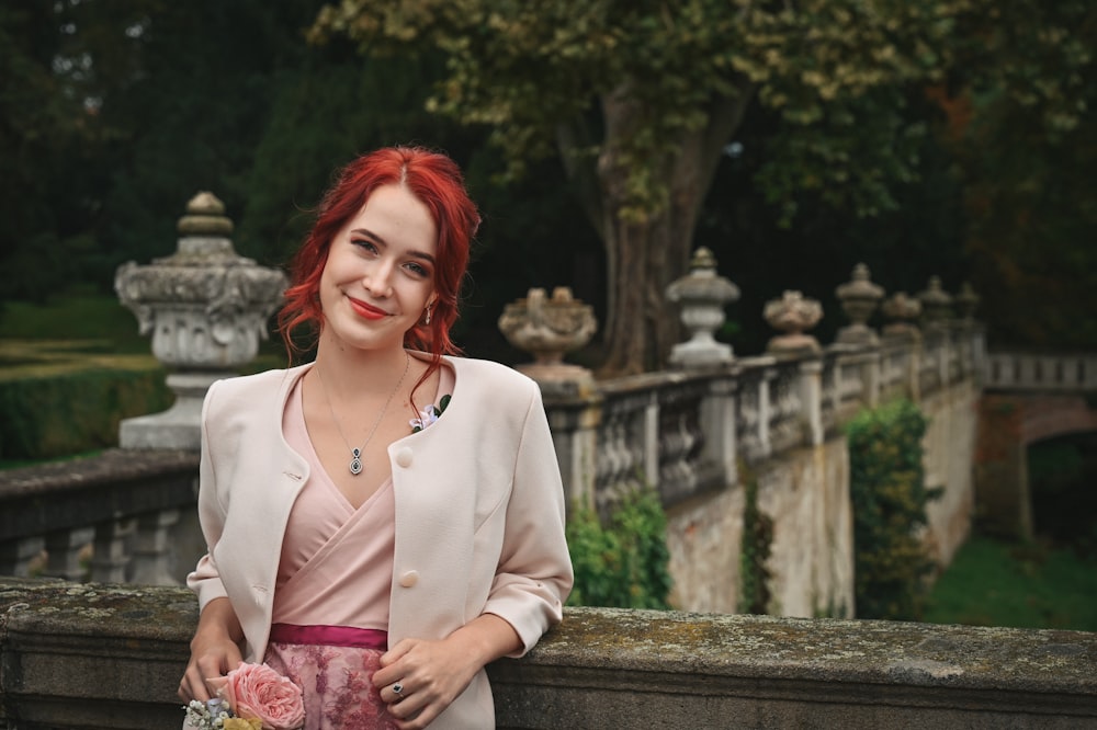 a woman with red hair is standing on a bridge