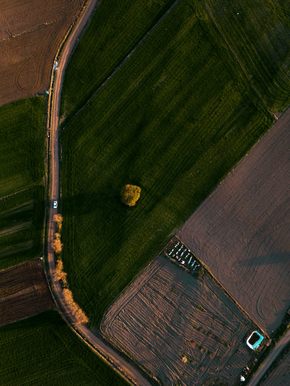 an aerial view of a farm field with a truck driving down the road