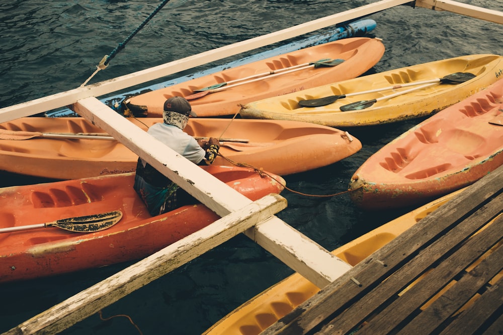 a man sitting on a dock next to a row of kayaks