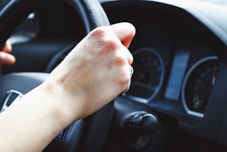 a person driving a car with their hand on the steering wheel