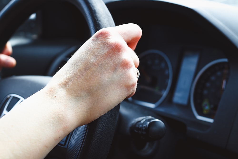 a person driving a car with their hand on the steering wheel